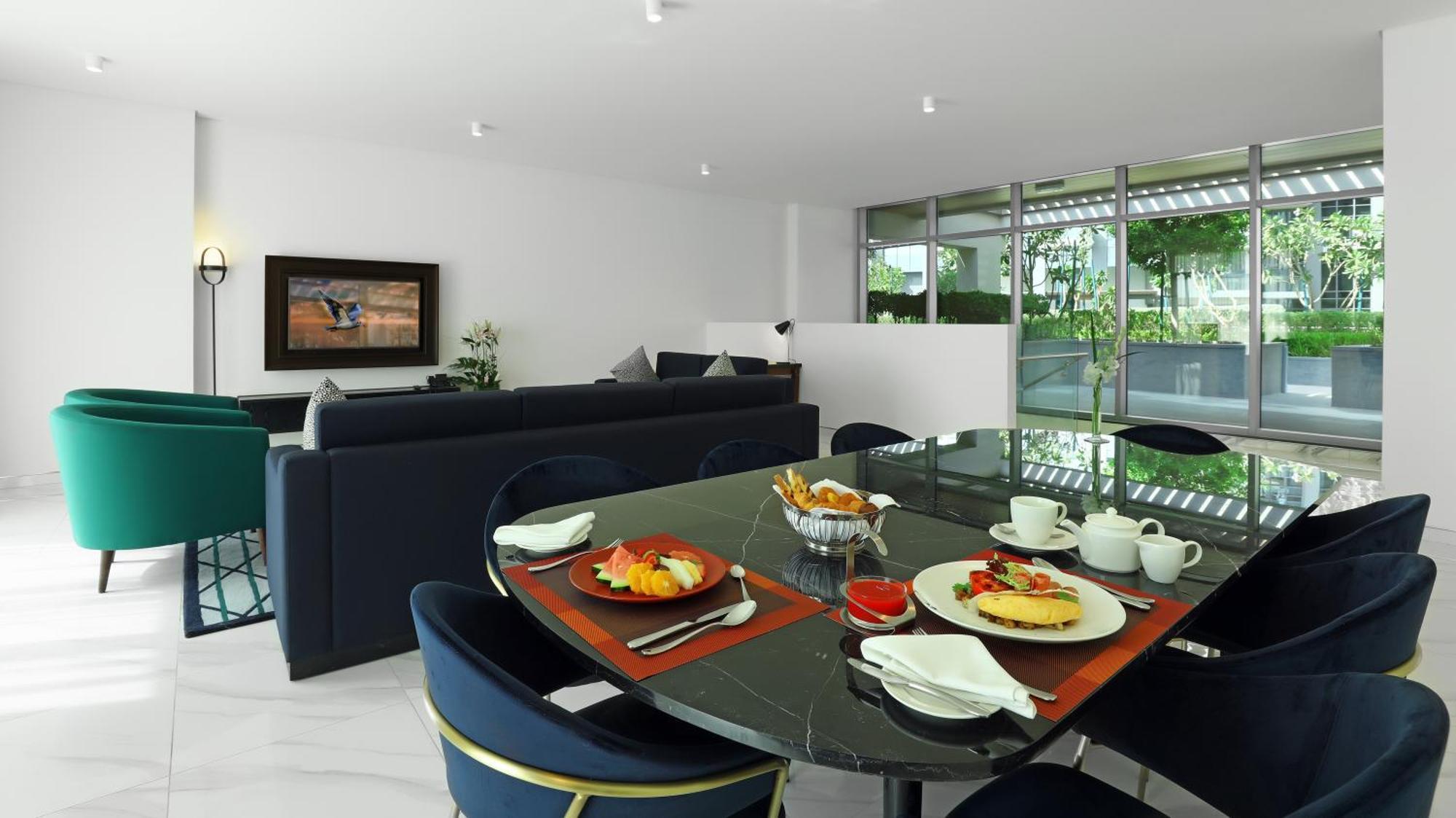 Millennium Atria Business Bay Aparthotel Dubai Luaran gambar The photo depicts a modern living space with a dining area and a seating area. In the foreground, there is a round dining table set with plates of food, including eggs, toast, and a small bowl of fruit, accompanied by cups and napkins. The table is c